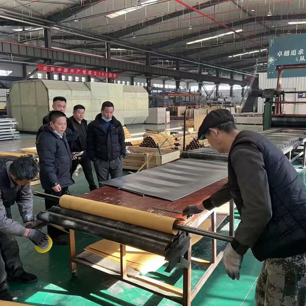 Our OSIDEK production and QC team overseeing the automated lamination and pressing process for medical-grade cleanroom purification panels on the factory floor.