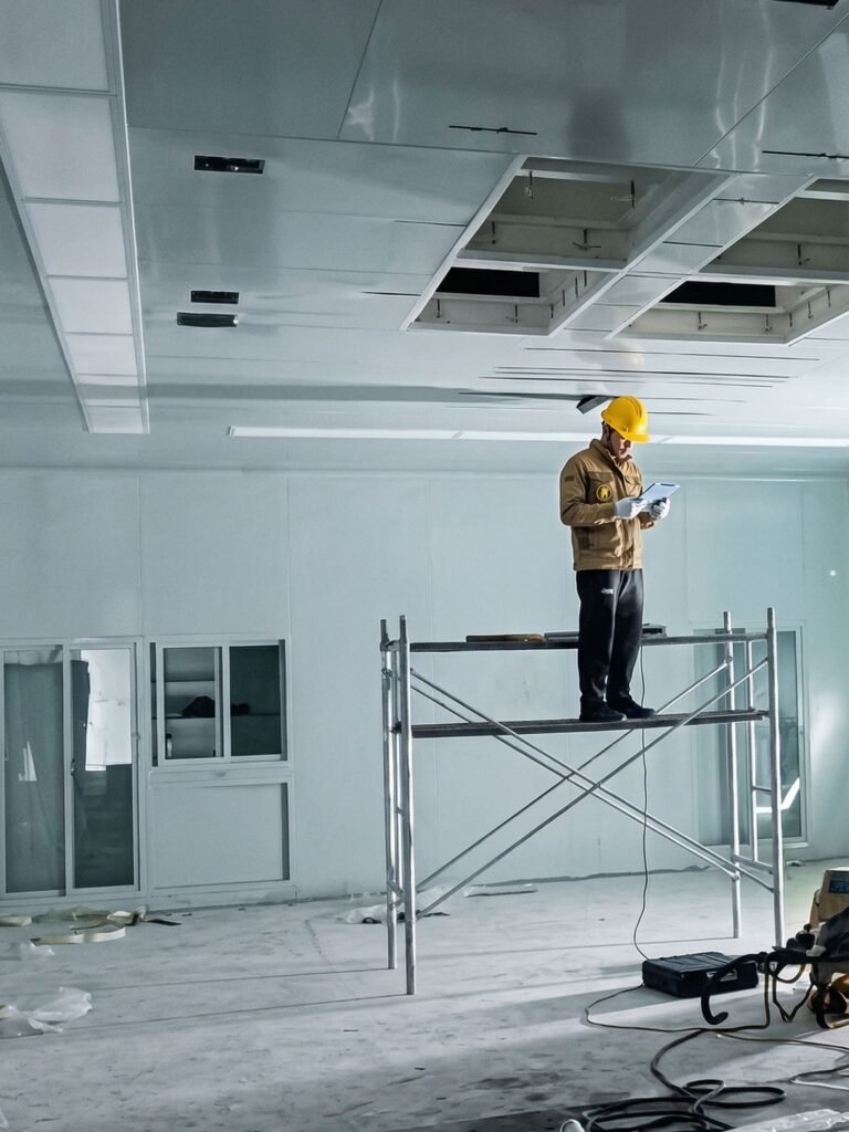 OSIDEK engineer on scaffolding installing a laminar airflow ceiling system during a turnkey operating room cleanroom renovation project.